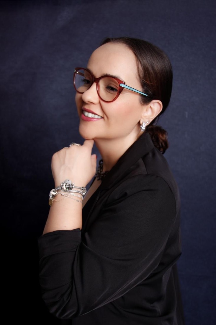 Fabiana Ribeiro sorrindo, de óculos, com a mão no queixo